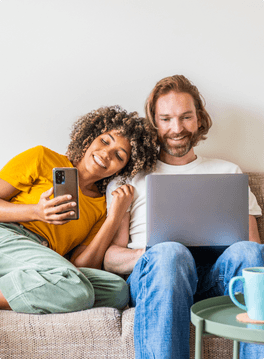 couple sitting on the couch using electronics