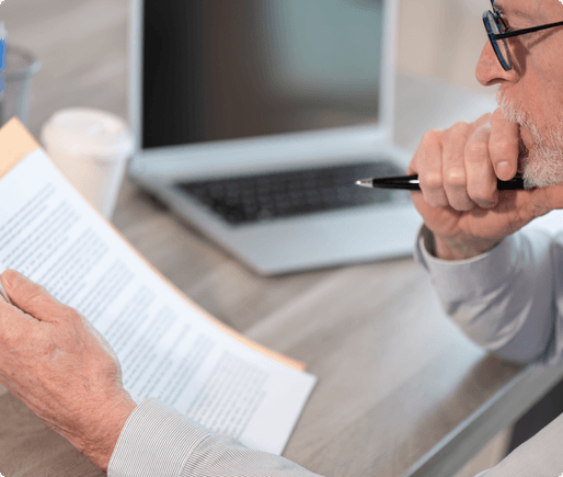 A man sitting at a desk holding a pen while reading a document