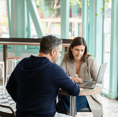 A couple sitting at a table looking at a laptop