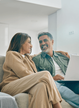 couple sitting on the couch using laptop