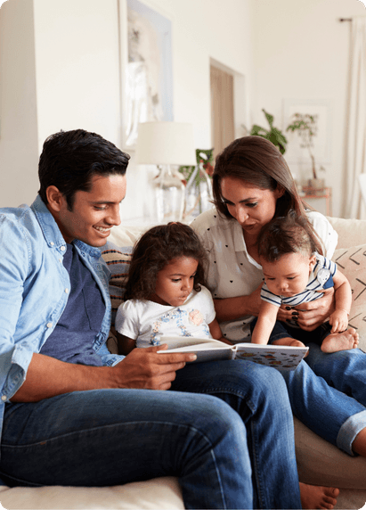 A family sitting on the couch reading a book