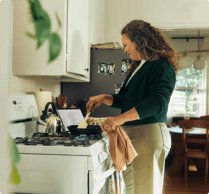 A woman in the kitchen cooking on the stove