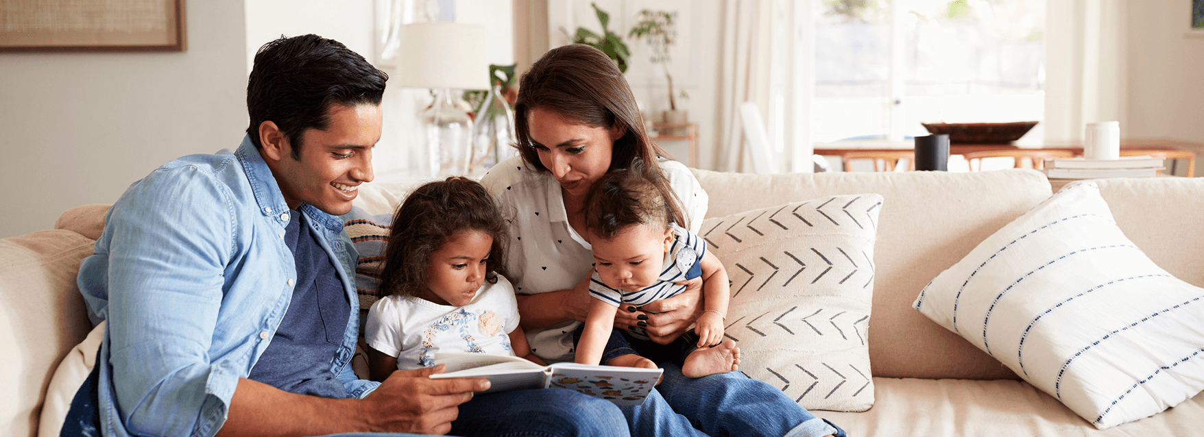 A family sitting on the couch reading a book